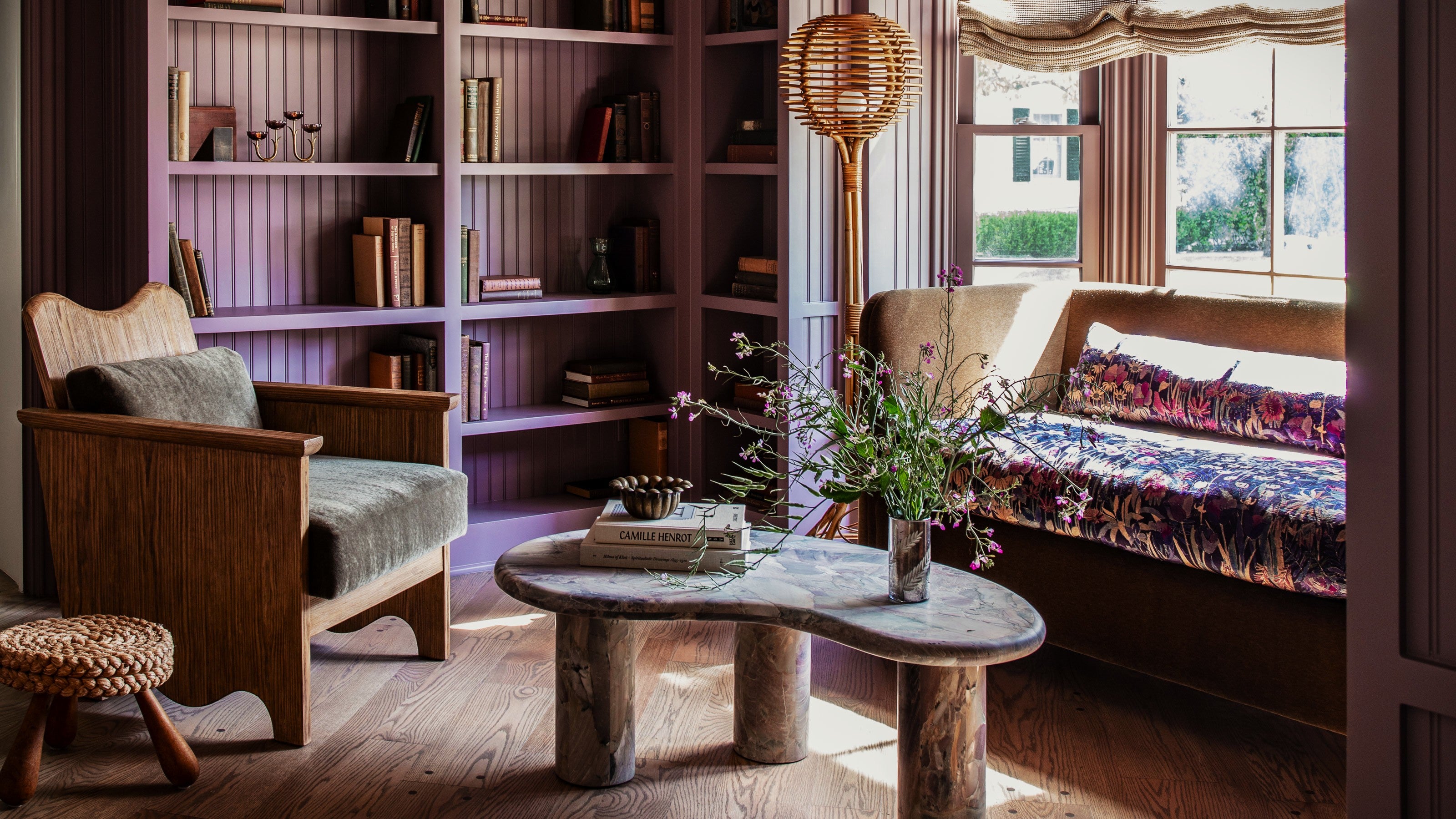 Cozy living room with wooden furniture, bookshelves, and a large window.